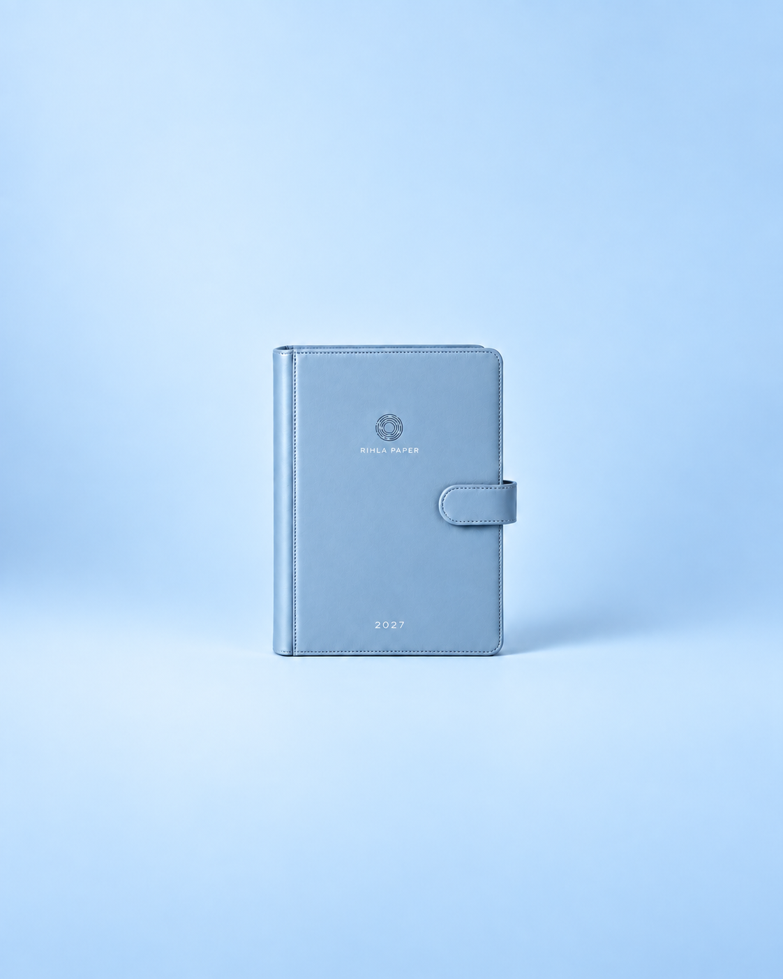The proposed mist-blue A5 binder with a simple tab closure. Final material and construction will be confirmed after sampling.